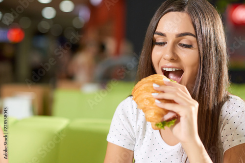 Hungry female biting croissant in cafe