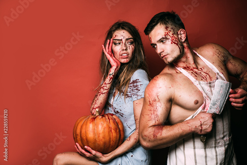 Halloween student party in blood. Couple of muscular man and bloody young woman with wounds and red blood. Terrifying zombie couple.