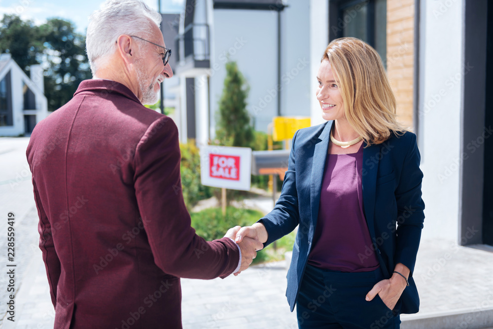 Shaking hand. Bearded grey-haired prosperous man shaking hand of estate broker after buying big luxury house Shaking hand. Bearded grey-haired prosperous man shaking hand of estate broker after buying big luxury house