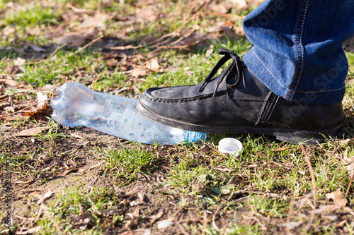 human trampled with the feet of plastic mineral water bottles and bottle caps on the grass in the park, the concept of environmental protection, fouling the environment