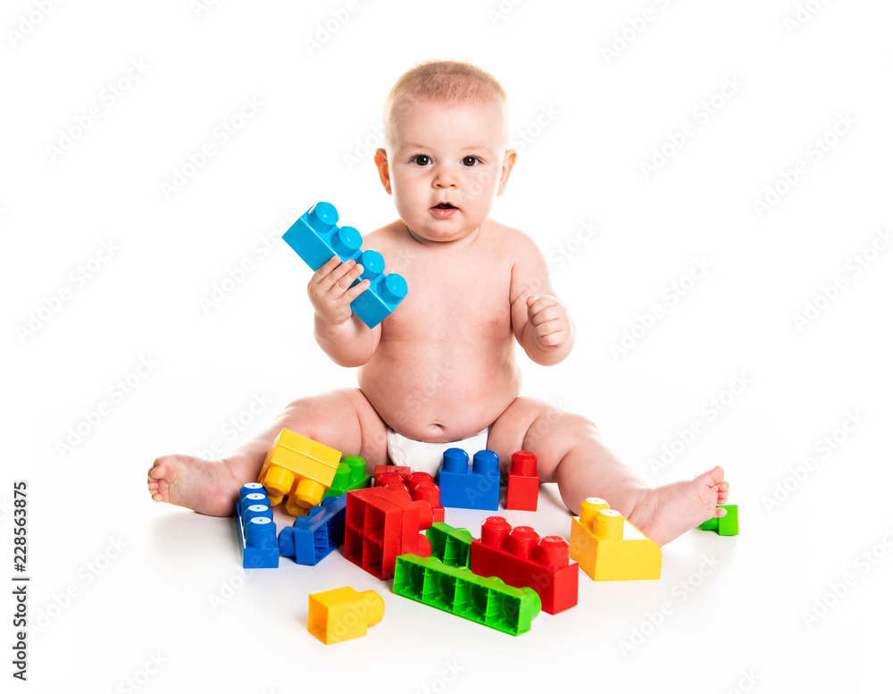 Baby boy plays with toy blocks over white background Baby boy plays with toy blocks over white background