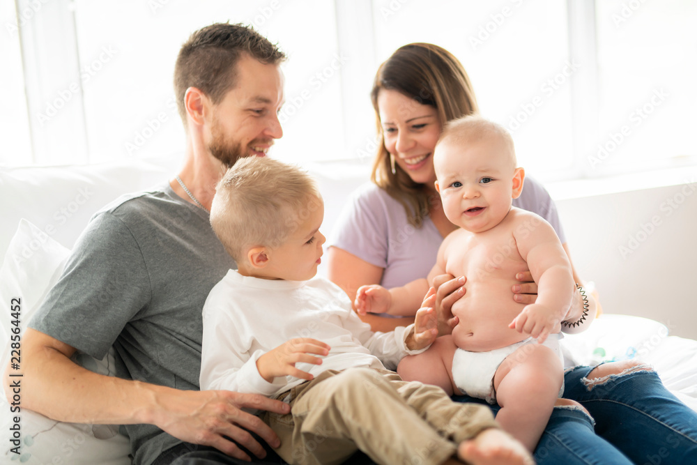 Family of four with baby having fun on bed Family of four with baby having fun on bed