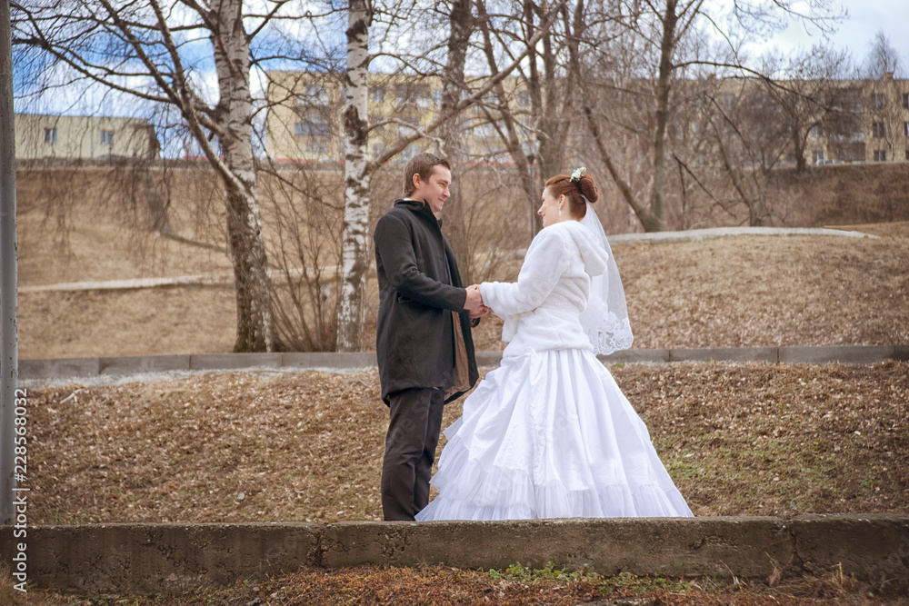 The bride and groom hold hands and look at each other on the street in the autumn. The bride and groom hold hands and look at each other on the street in the autumn.