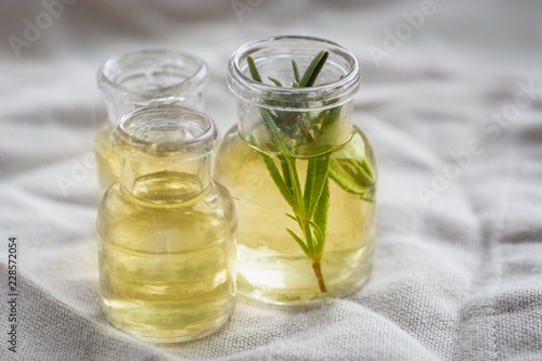 Rosemary essential oil in small bottles with a fresh rosemary inside closeup