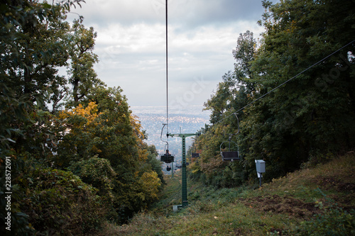 A cabin of cableway above the autumn forest, city Budapest in the background