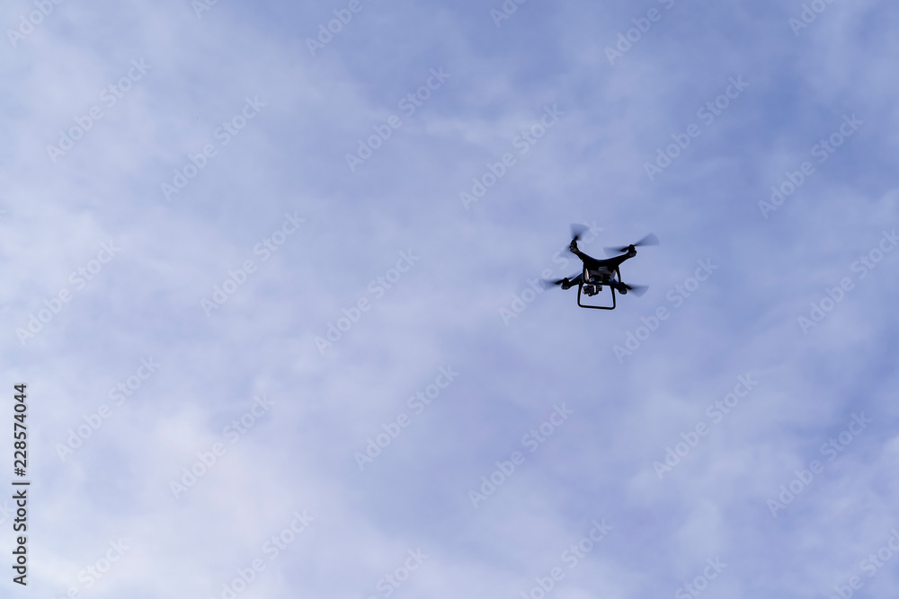 Flying drone with blue sky background controlled by professional photographer. Flying drone with blue sky background controlled by professional photographer.