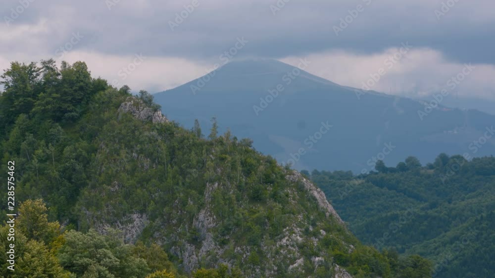 Romanian mountain landscape with wooded hills and a mountain peak in background. Nice blue sky line pver the mountain Romanian mountain landscape with wooded hills and a mountain peak in background. Nice blue sky line pver the mountain