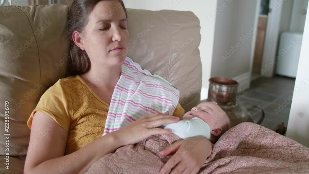 A Tired Young Mother Sleeping On Couch While Holding A Newborn Girl A Tired Young Mother Sleeping On Couch While Holding A Newborn Girl
