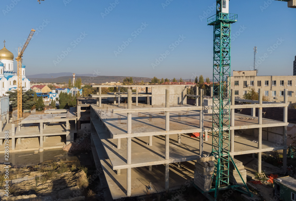 Fototapeta premium High rise building under construction. The site with cranes against blue sky.