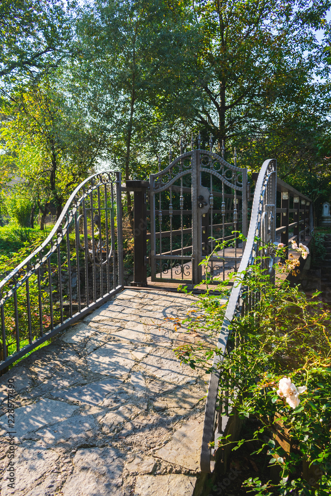 View of closed decorative  iron gate leading to a bridge over a river in autumn. Samobor near Zagreb, Croatia. 
