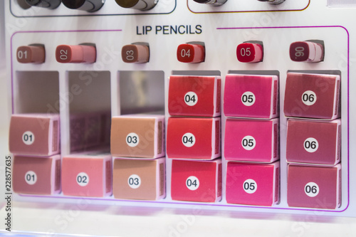 Decorative cosmetics samples, testers. Various lip pencils in a showcase of beauty shop. Different cosmetics in modern shop. Retail, shopping. Selective focus