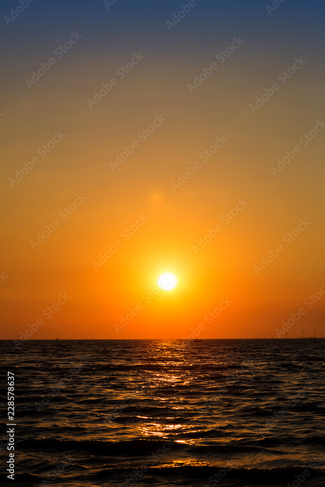 Naklejka premium Bright sunset with large yellow sun under the sea surface. Sunset over sea landscape. Beautiful sunset with sky over calm sea in tropical island