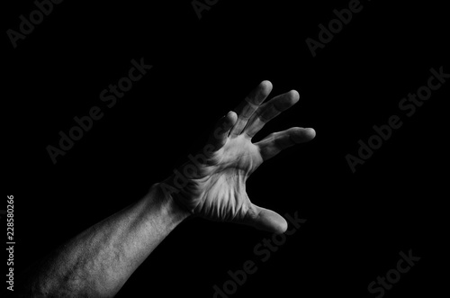 Men's hand reaches up out of the darkness to the light.