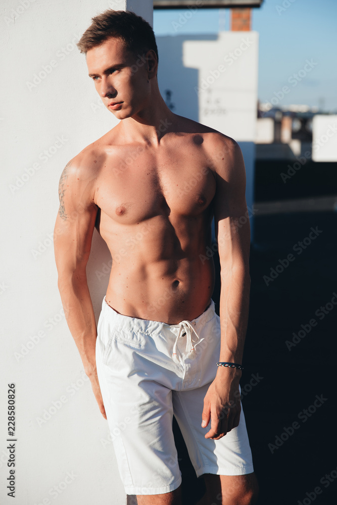 Obraz premium Male model, sporty man, juicy guy on the roof, man in a white shorts