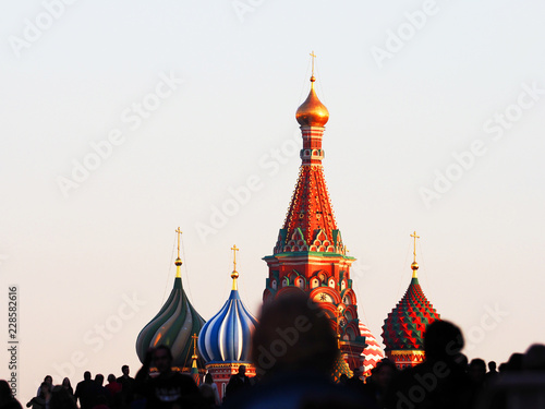 Domes of Saint Basil's Cathedral against sunset sky, people walk on the Red square (out of focus), Moscow Kremlin, Russia