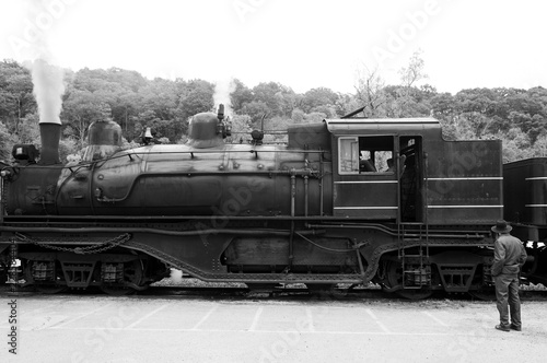Amish man looking at a steam locomotive at the train station in black and white