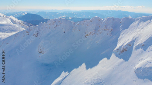 AERIAL: Flying towards the high summit of a snow covered mountain in the Alps.