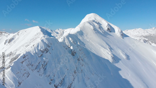 AERIAL  Cinematic shot of a majestic snowy mountain ridge in the sunny Alps.