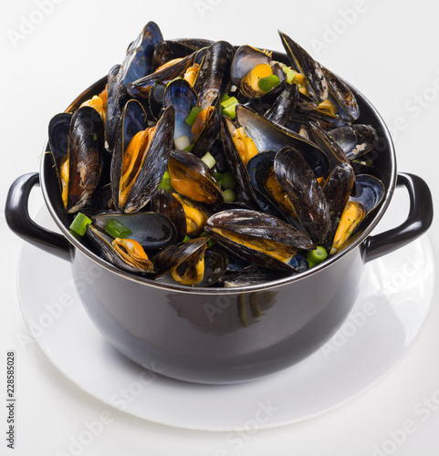 Black pan with cooked with green onion, parsley marinated high quality mussels