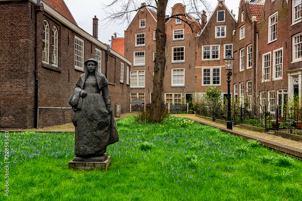Fototapeta premium Amsterdam, Holandia - 9 kwietnia 2018: Begijnhof to jeden z najstarszych wewnętrznych sądów w Amsterdamie. Skupia się na nim zespół zabytkowych budynków, głównie mieszkalnych.