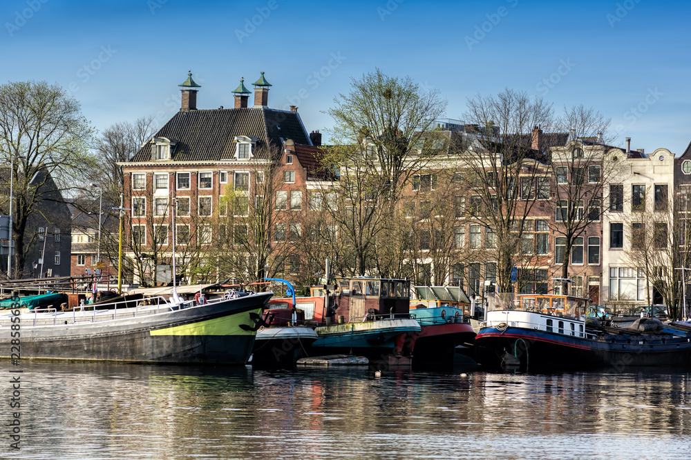 Obraz premium Amsterdam, Holandia - 10 kwietnia 2018: Amsterdam gród z typowymi holenderskimi domami i łodziami z Oosterdok w Holandii.