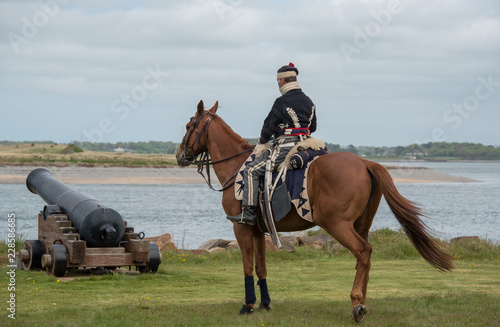Reenacter Hussar on horse next to cannon © Noel