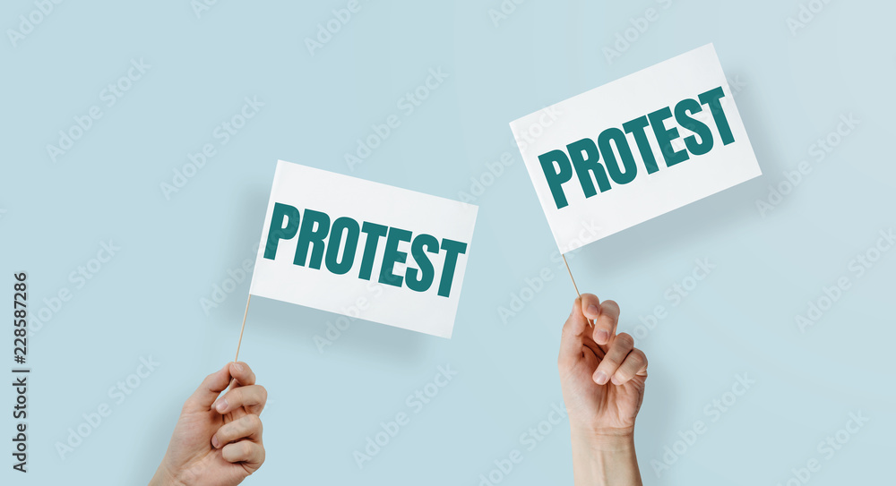 Hands are holding flags with the word PROTEST. Linking to protest, rebellion against the state, employer. Manifestation against ill-treatment, increases, small incomes. Hands are holding flags with the word PROTEST. Linking to protest, rebellion against the state, employer. Manifestation against ill-treatment, increases, small incomes.