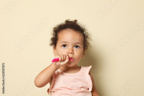 Cute African-American girl with toothbrush on color background