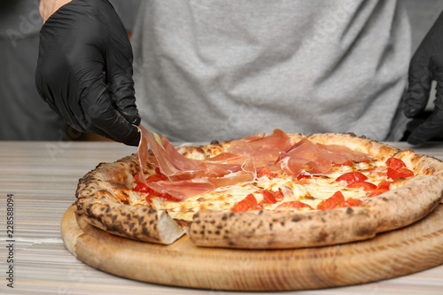 Professional chef preparing Italian oven baked pizza in restaurant, closeup