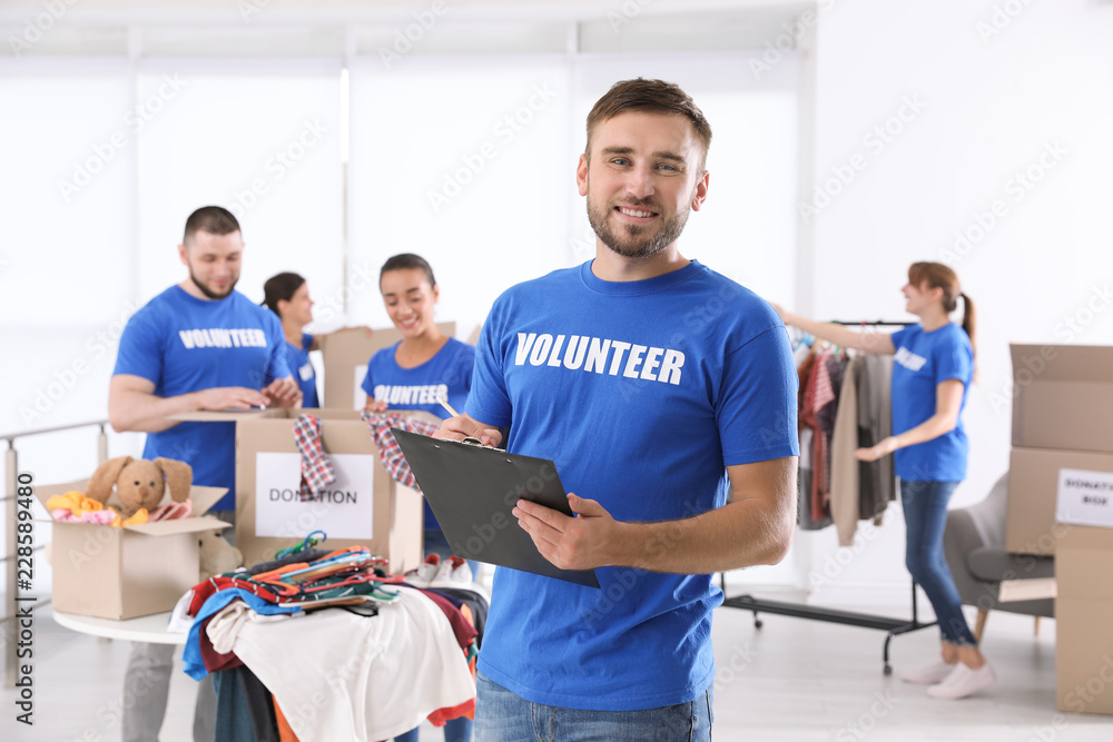 Male volunteer with clipboard listing donations indoors Male volunteer with clipboard listing donations indoors