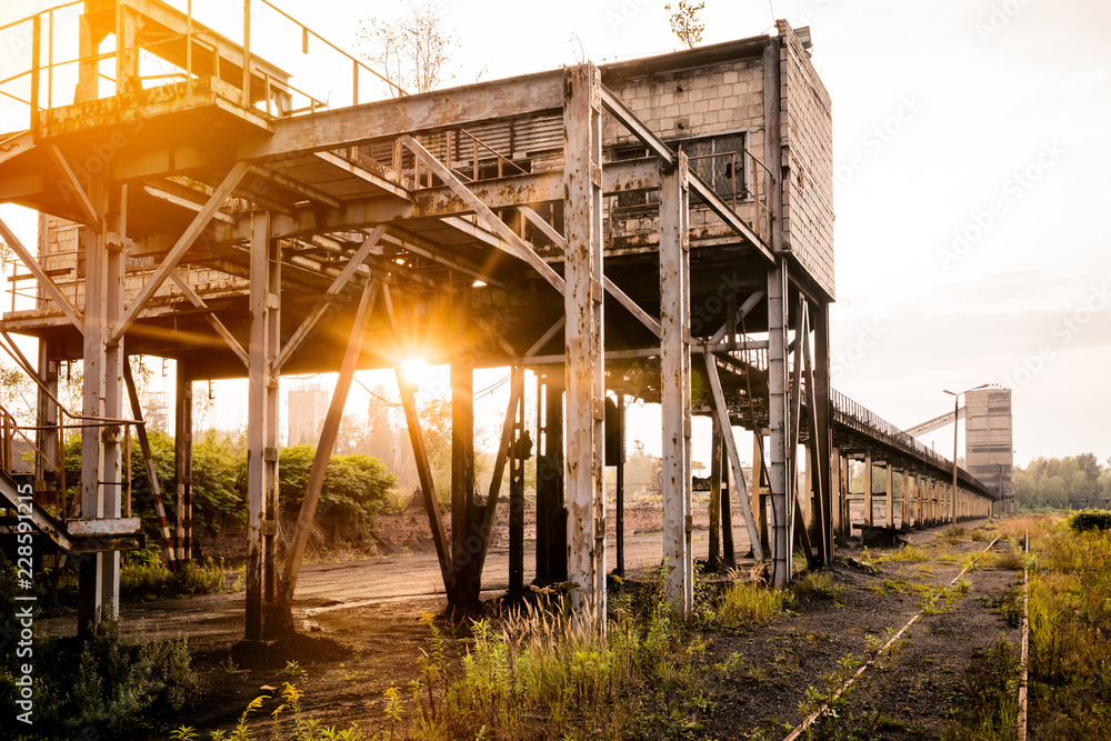 Industrialism in Silesia. A view of an old unused charging station with coal. Coal conveyor. The place of arrival of trains against the background of the setting sun.