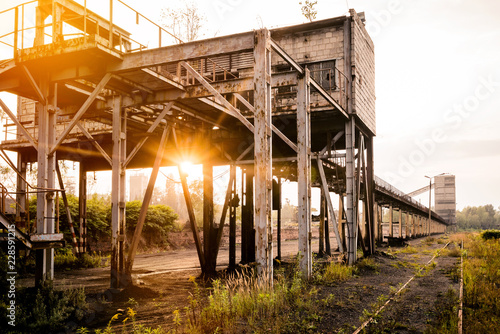 Industrialism in Silesia. A view of an old unused charging station with coal. Coal conveyor. The place of arrival of trains against the background of the setting sun.