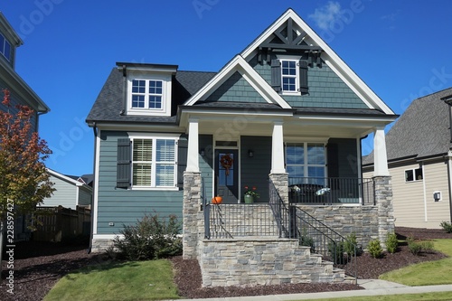 Canvas Print Exterior view of a two-story suburban home with a stone porch in autumn
