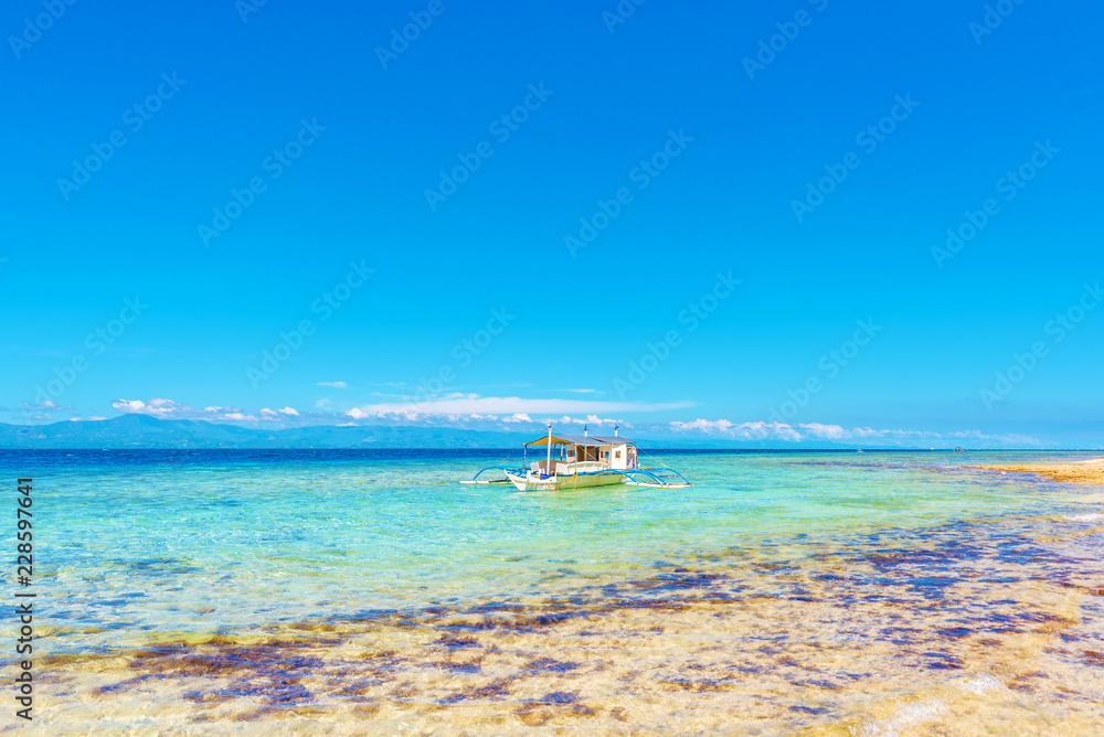 Crystal clean ocean with coral and a boat in Moalboal, Cebu, Philippines. Copy space for text.