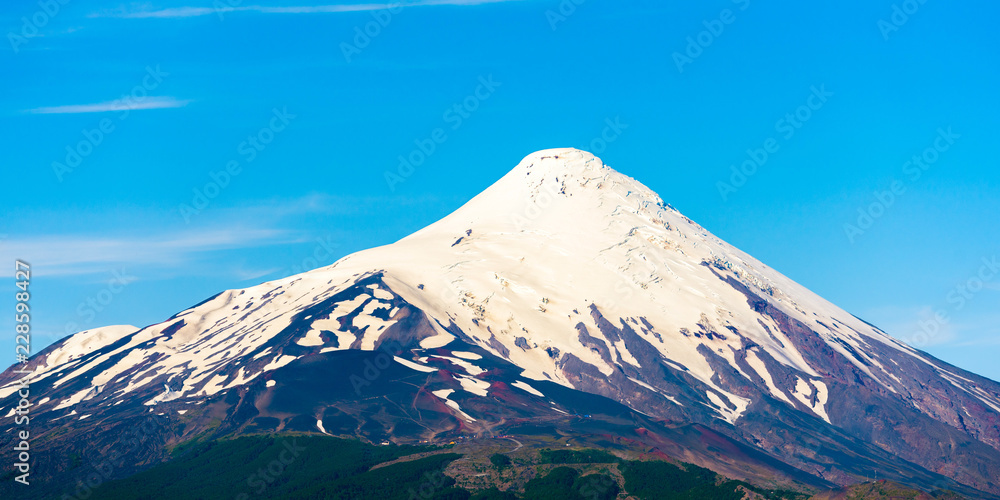 The top of the volcano Osorno in national park Vicente Perez Rosales, Chile. Isolated on blue background.
