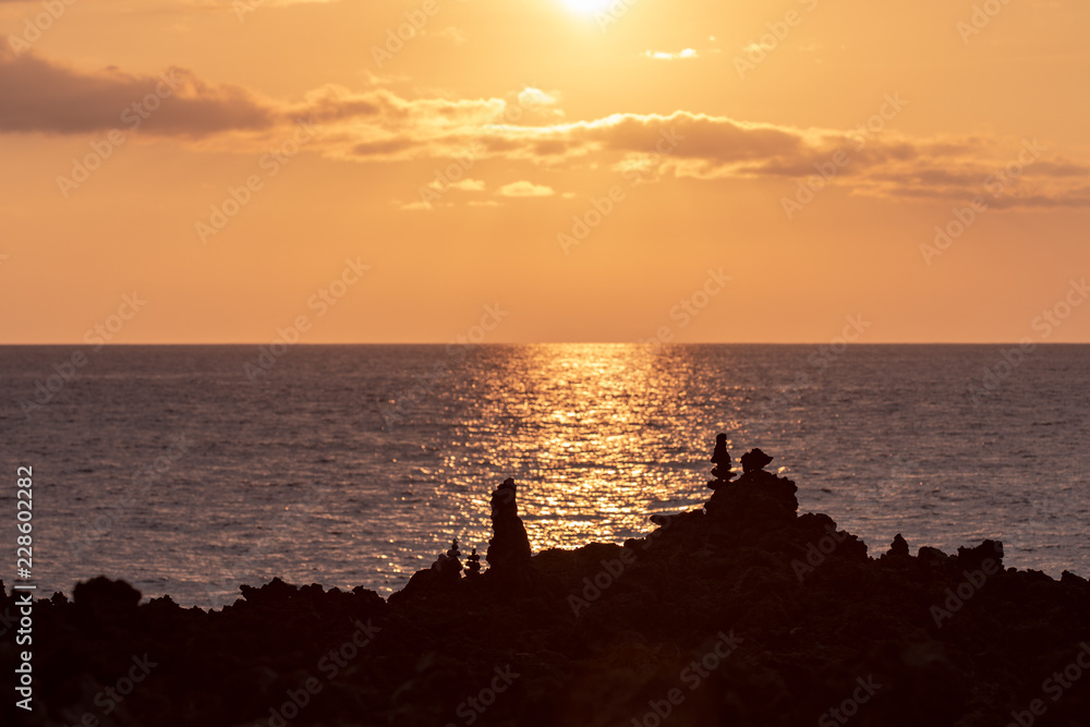 Tall rock formations with sunset over the Pacific ocean in the background