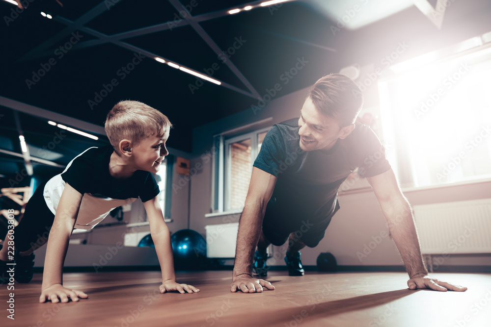 Obraz premium Father And Son Are Doing Push Ups In The Gym.