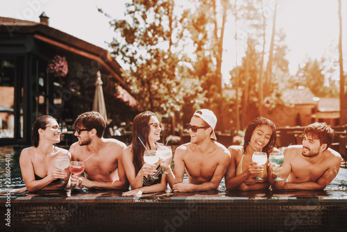 Young Smiling Friends with Cocktails at Poolside