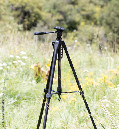 Tripod for the camera on a background of grass