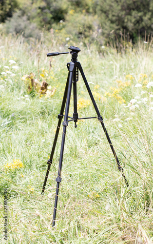Tripod for the camera on a background of grass