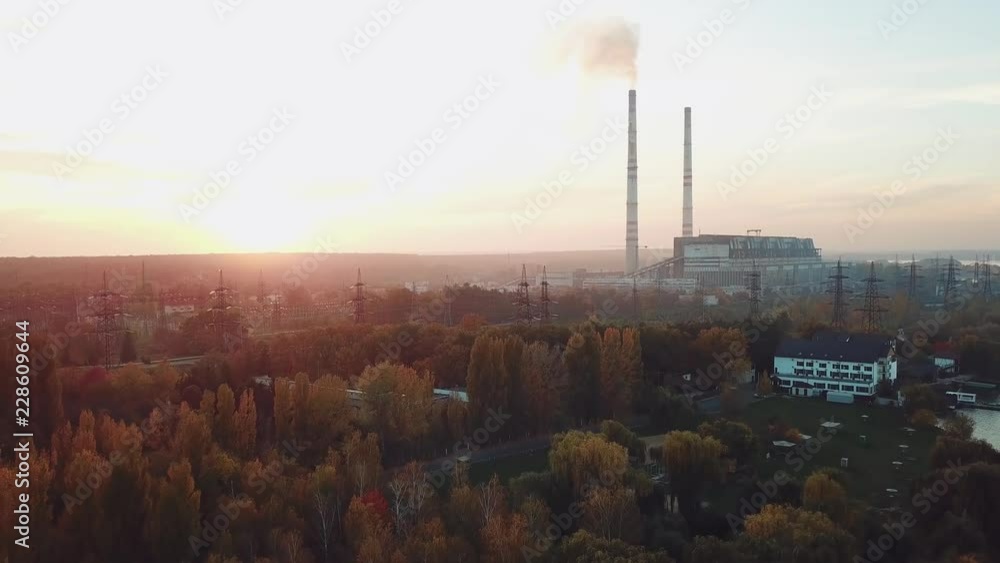 power plant with two pipes is located on the outskirts of the city on the bank of river. Camera motion back. Aerial view power plant with two pipes is located on the outskirts of the city on the bank of river. Camera motion back. Aerial view