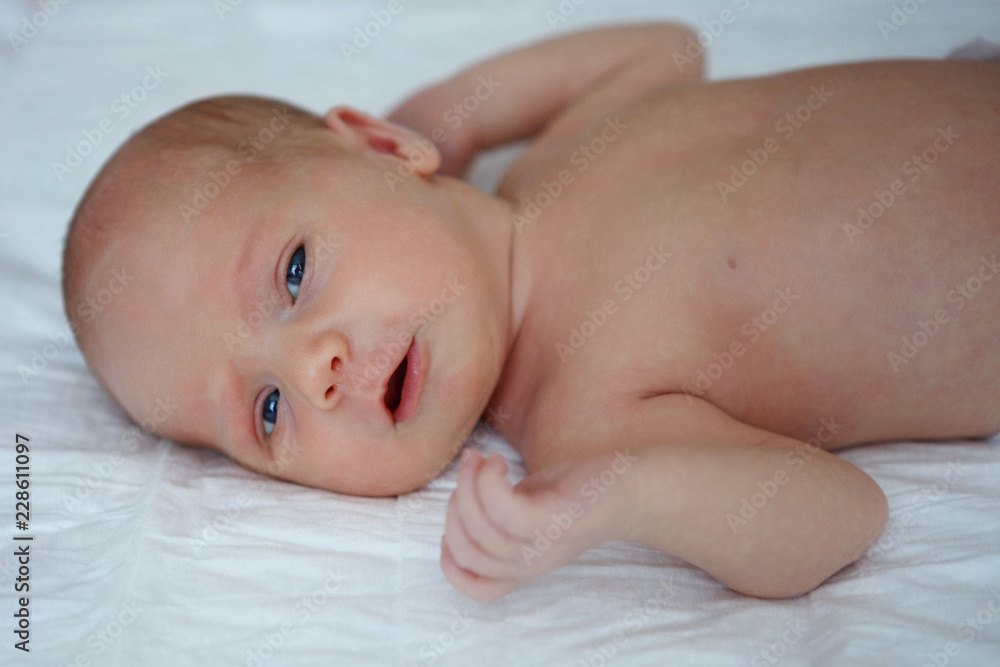 The baby naked lies on her back. The baby naked lies on her back.