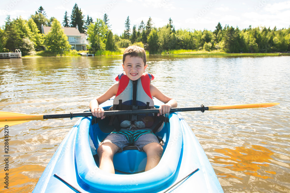 Summer vacation Portrait of happy cute boy kayaking the on river Summer vacation Portrait of happy cute boy kayaking the on river