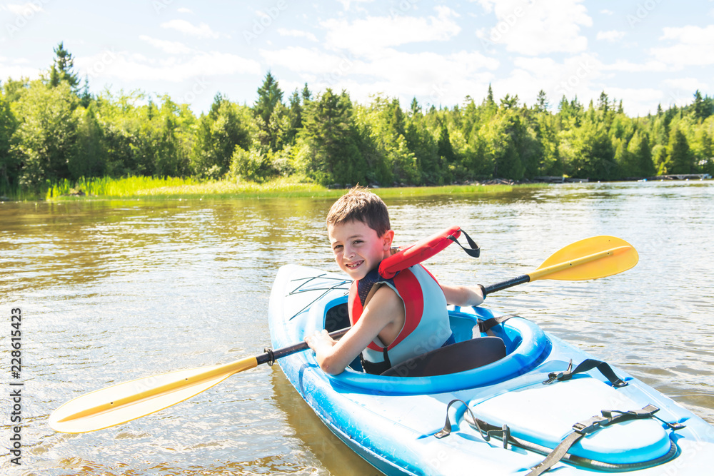 Summer vacation Portrait of happy cute boy kayaking the on river