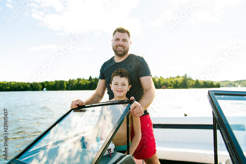 Man driving boat on holiday with his son kid