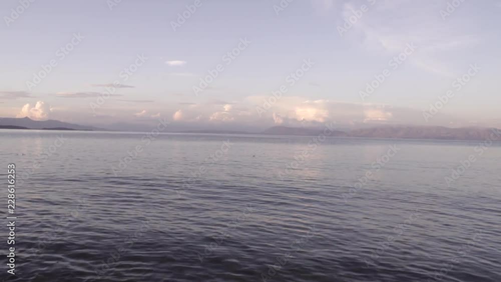 Warm sunset clouds over gentle sea landscape in Corfu Greece Warm sunset clouds over gentle sea landscape in Corfu Greece