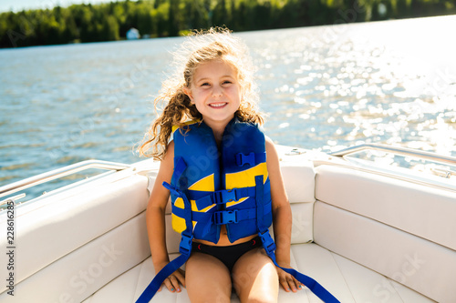 child with safety vest on the lake boat