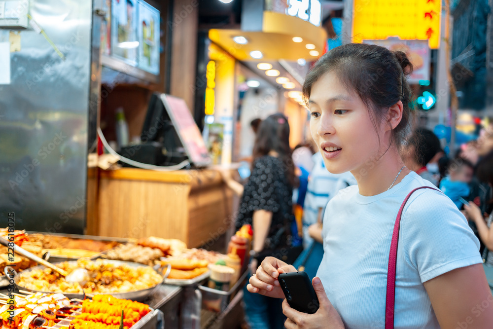 Fototapeta premium Dziewczyna próbuje lokalnego jedzenia ulicznego w Hongkongu - kulki rybne curry