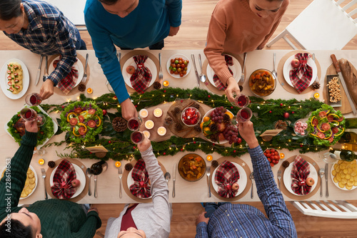 Young people clinking glasses over Christmas dinner table