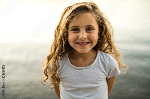 Cute child girl on a wooden platform by the lake.